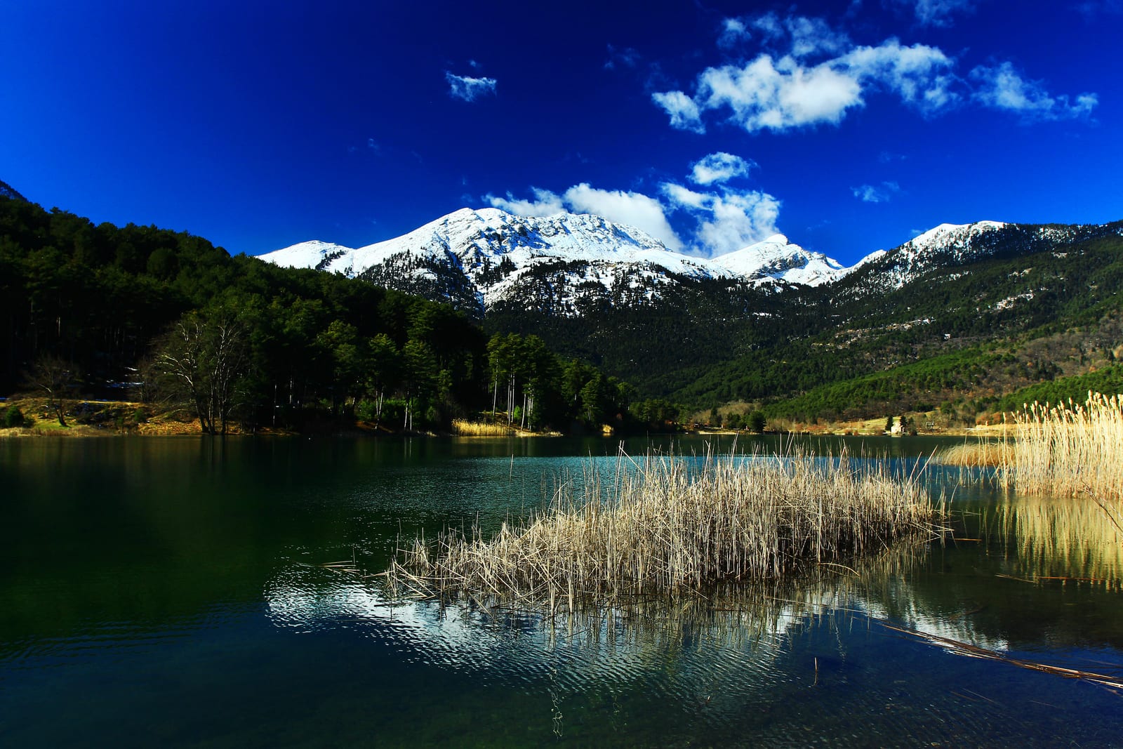 Der verschneite Ziria spiegelt sich in einem Bergsee